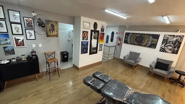 Área de atendimento com quadros de arte nas paredes, poltronas e maca