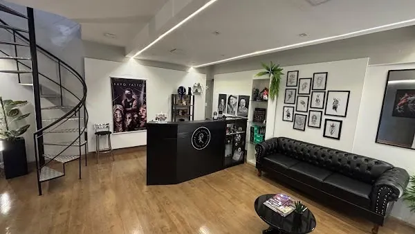 Recepção do studio com balcão preto com a rosa do logo, sofá Chesterfield e escada em caracol